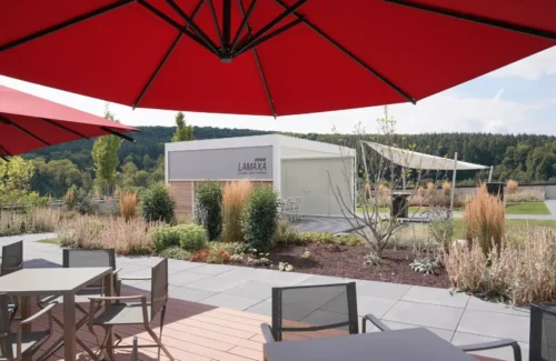 Moderne Terrasse mit roten Sonnenschirmen und Blick auf ein Lamellendach