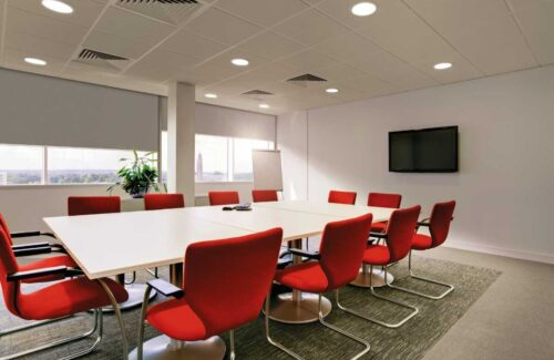 Moderner Konferenzraum mit roten Stühlen und großem Tisch