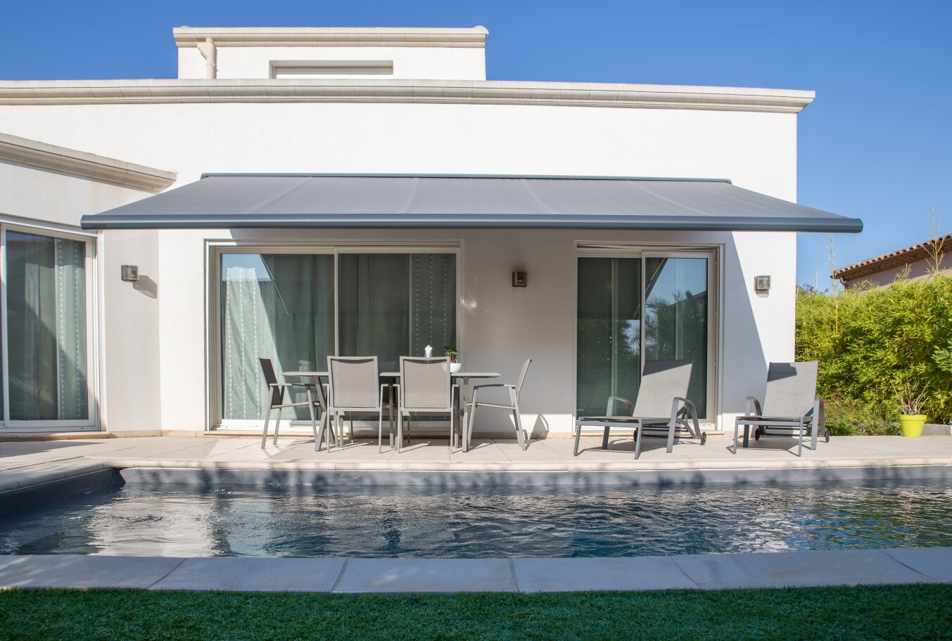 Die Brustor B50 XL bietet großfläche Beschattung einer Terrasse vor einem Pool.