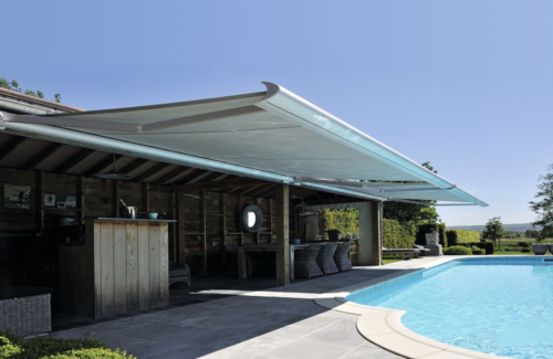 Die Brustor B50 Kassettenmarkise bietet Sonnenschutz an einer Terasse mit angrenzendem Pool