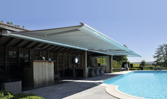 Die Brustor B50 Kassettenmarkise bietet Sonnenschutz an einer Terasse mit angrenzendem Pool