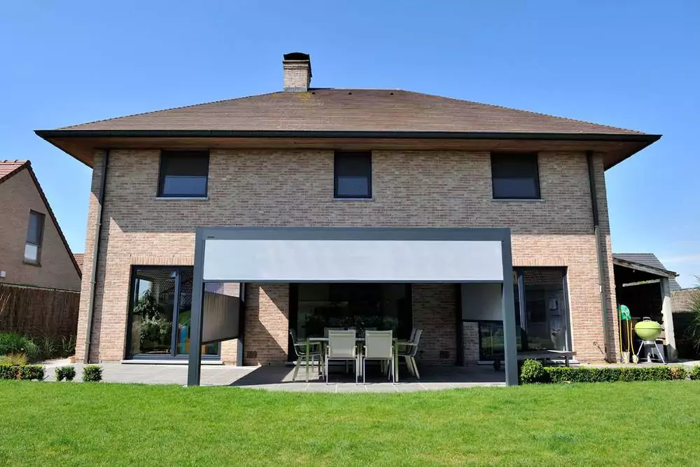 Backsteinhaus mit Lamellendach auf Terrasse und Seitenmarkise