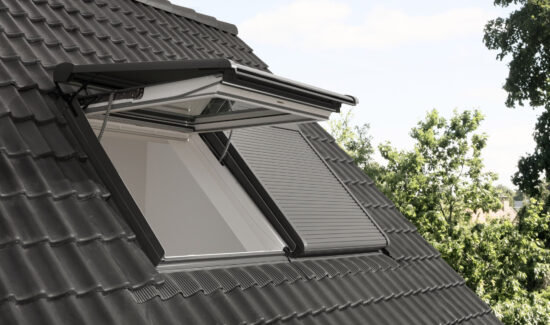 Elektrischer Rollladen für Dachfenster, der das Kippen der Dachfenster ermöglicht. Einmal ist ein Dachfenster mit geschlossenem Rollladen gekippt und ein anderes geschlosssen.