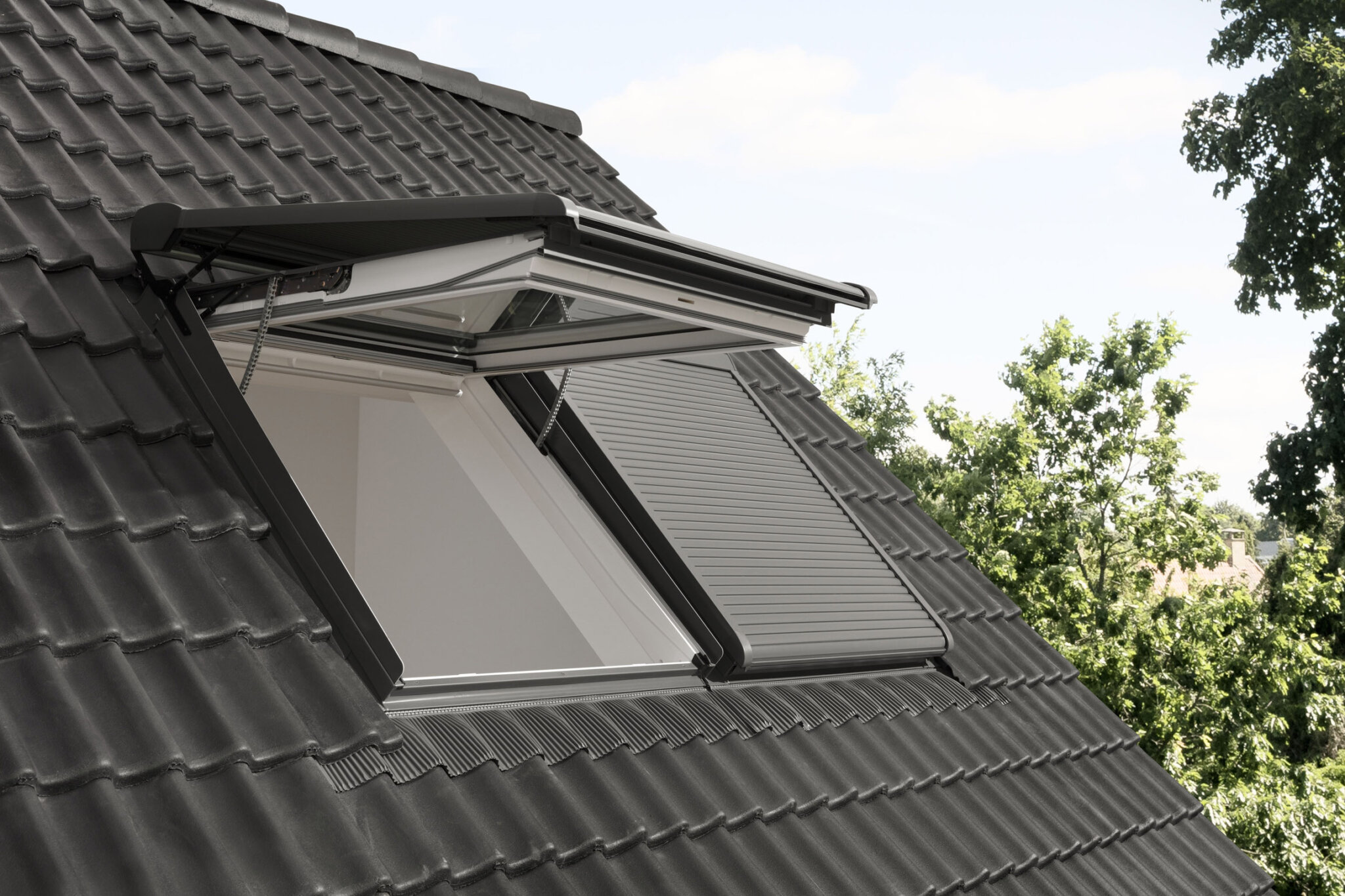 Elektrischer Rollladen für Dachfenster, der das Kippen der Dachfenster ermöglicht. Einmal ist ein Dachfenster mit geschlossenem Rollladen gekippt und ein anderes geschlosssen.