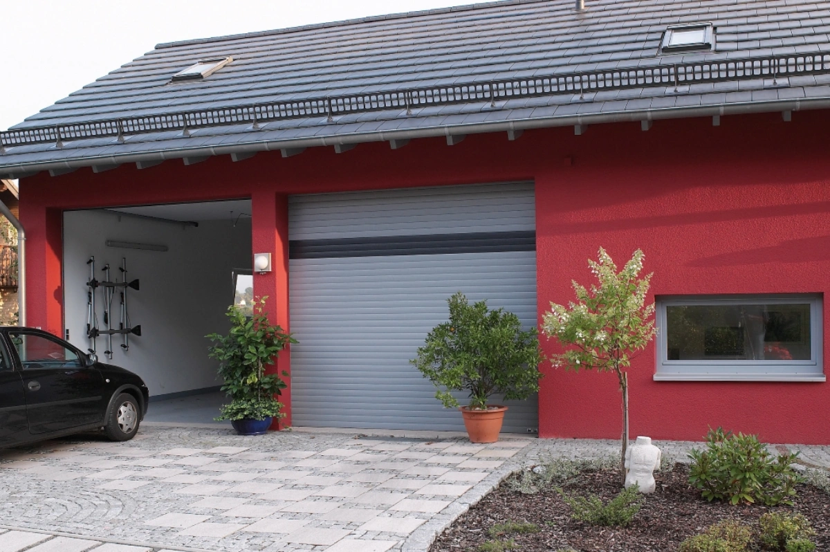 Eine Doppelgarage mit ROMA Garagentoren, das eine geschlossen, das andere geöffnet mit einem Auto davor.