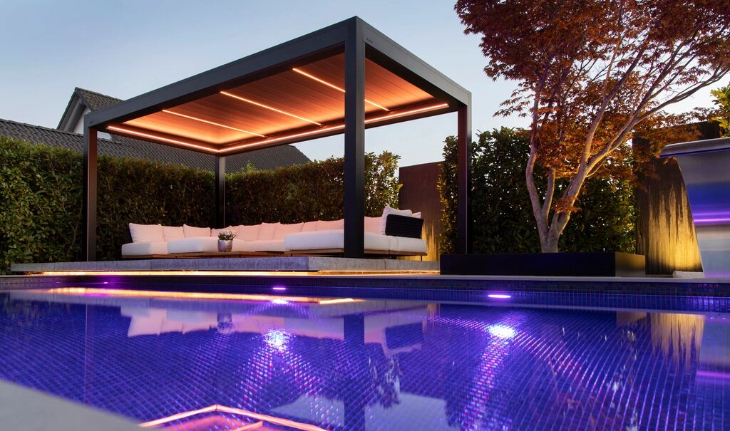 Eine beleuchtete Brustor B200 XL über eine Lounge neben einem Pool.