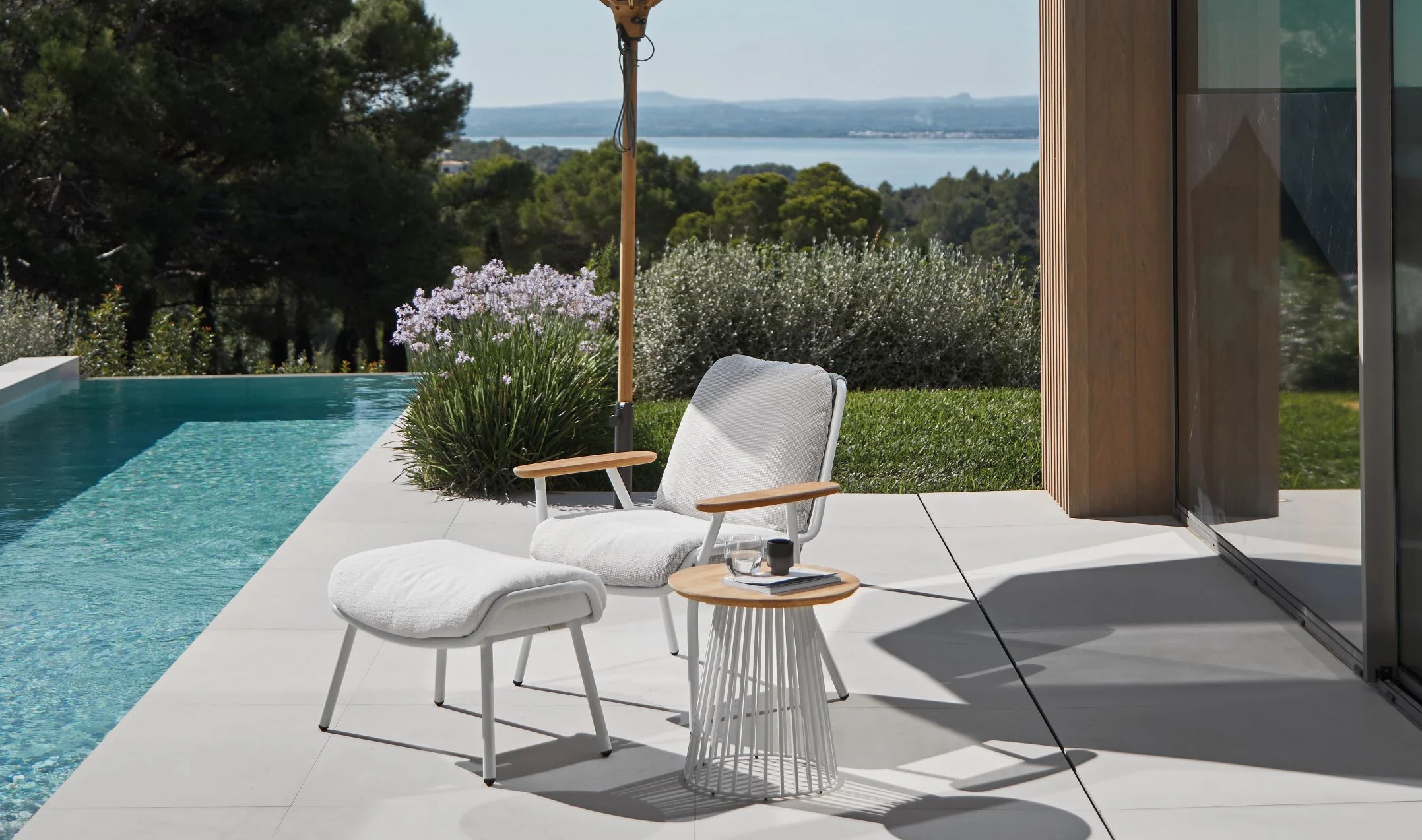 Sessel und Hocker der Variante BASSO Gartenmöbel von Solpuri neben einem Pool.