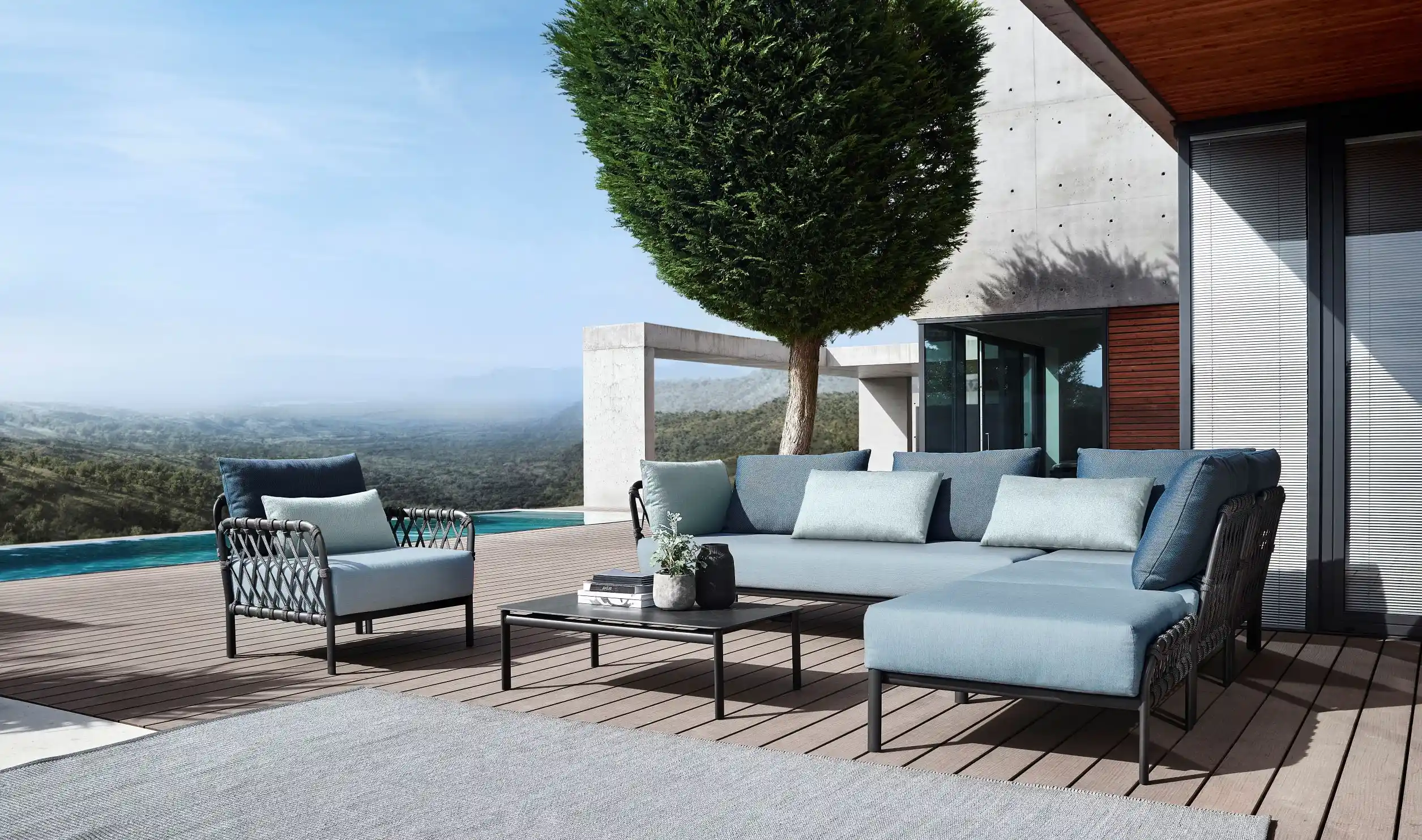 Auf einer Terrasse gruppiert sich eine CARO Lounge mit einem gleichartigen Sessel aus dem Sortiment der Terrassenmöbel von Solpuri.