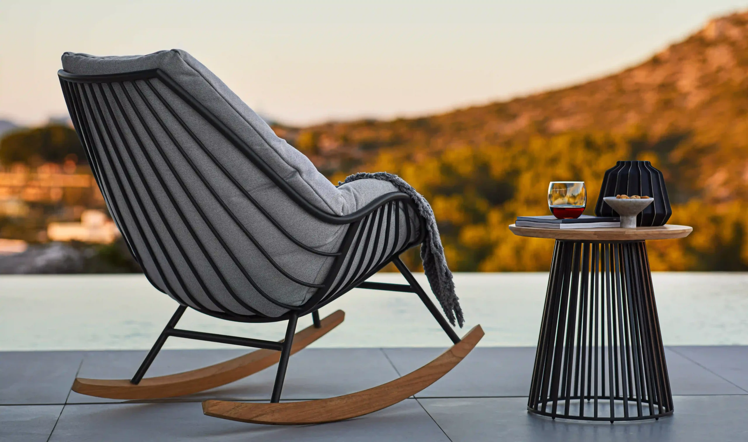 Eine Solpuri Liege der Variante CHILL steht vor einer weiten Aussicht gemeinsam mit einem GRID Beistelltisch.