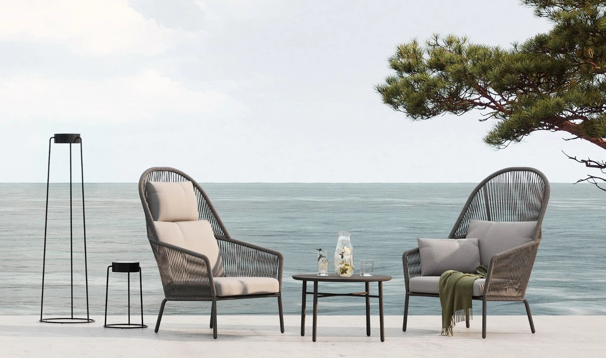 Gemütliche LOOP Hochlehner Sessel stehen auf einer Terrasse am Meer.