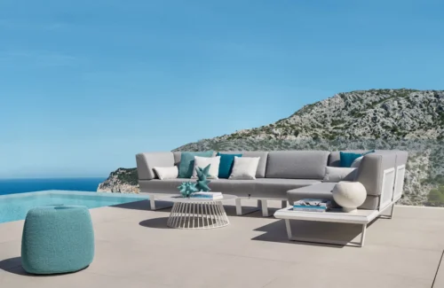 Lounge "BOOM" der Terrassenmöbel von Solpuri mit Beistelltisch neben einem Pool vor Meer und Berg.