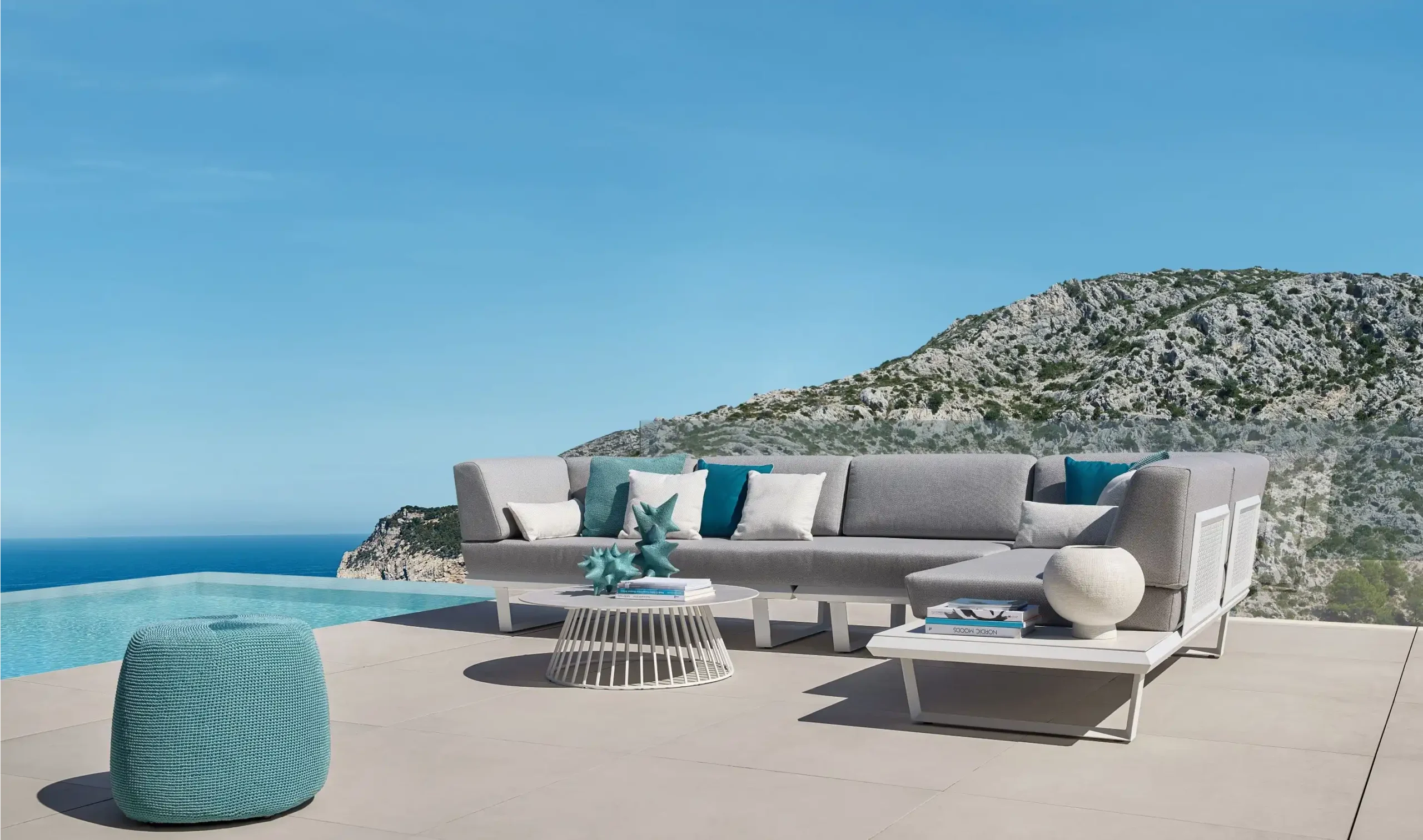 Terrassenmöbel der Marke Solpuri lassen sich auch aus unterschiedlichen Linien kombinieren. Hier zu sehen sind eine BOOM Lounge mit Beistelltischen KNUFF & GRID bei einem Pool.