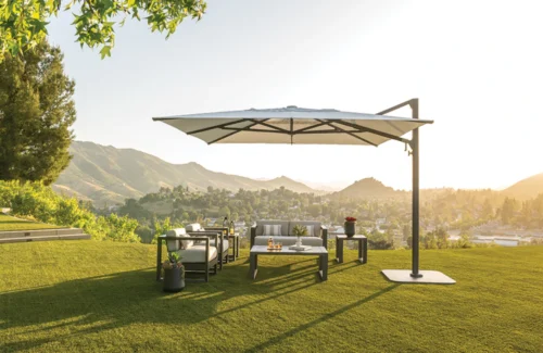 Ein Shademaker Polaris Sonnenschirm in eckiger Form beschattet einen Outdoor-Sitzbereich.