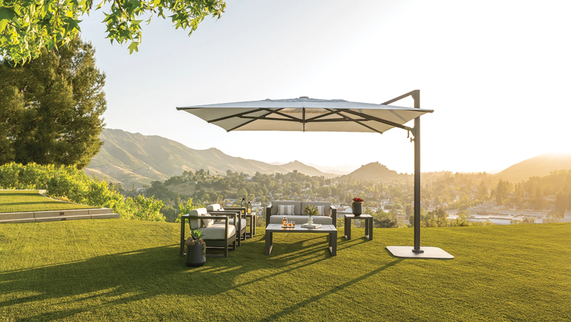 Ein Shademaker Polaris Sonnenschirm in eckiger Form beschattet einen Outdoor-Sitzbereich.