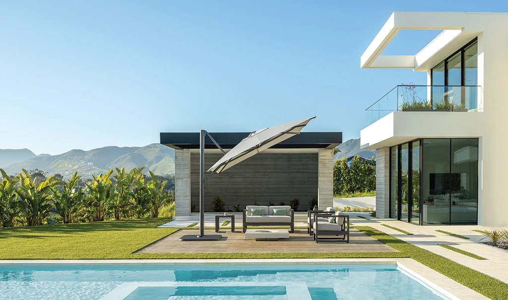 Bei einem modernen Haus mit Pool beschattet ein geneigter Shademaker Polaris Sitzgelegenheiten neben dem Wasser.