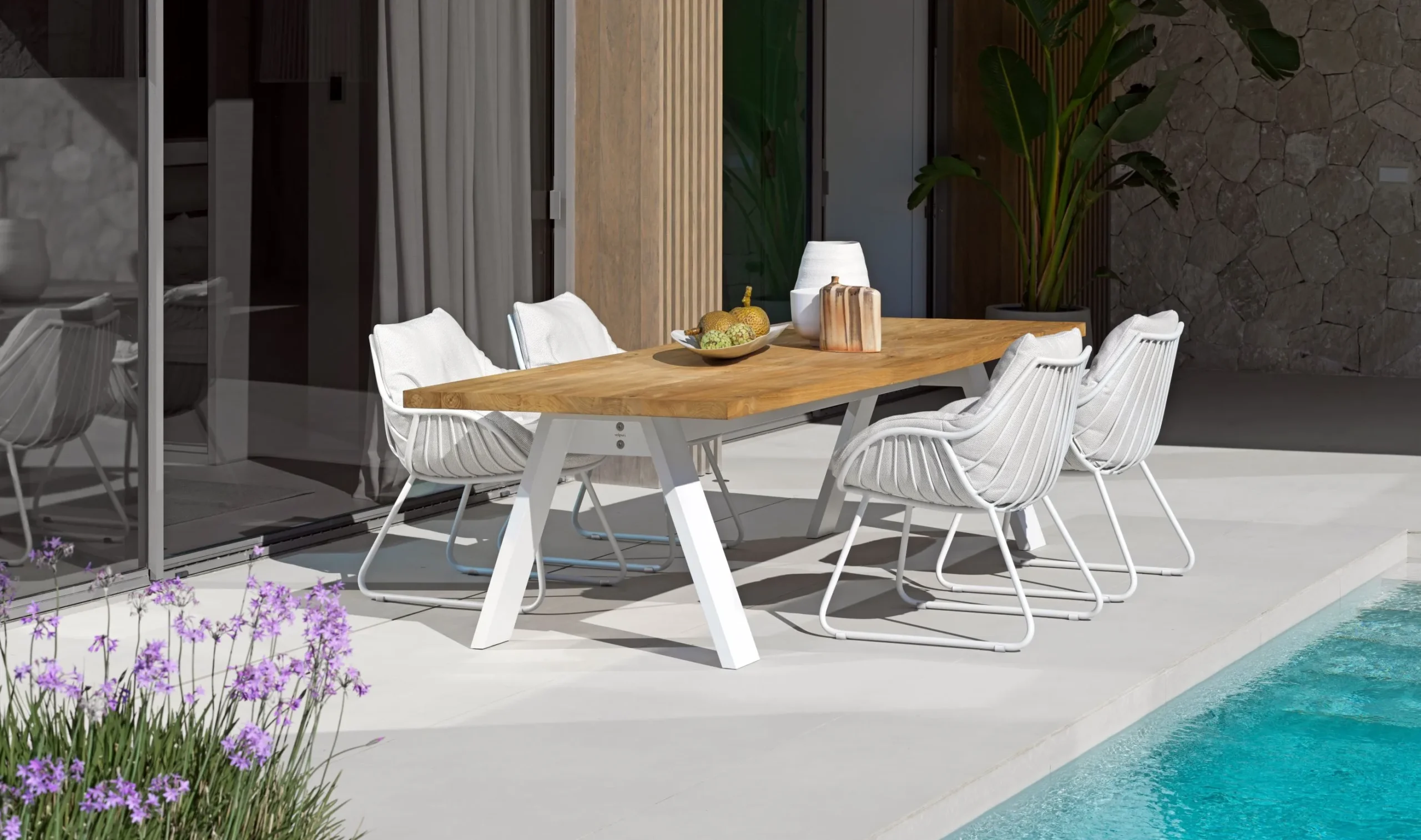 Solpuri Terrassenmöbel Esstisch "TIMBER" und vier "CHILL" Dining Sessel auf der Terrasse neben einem Pool.