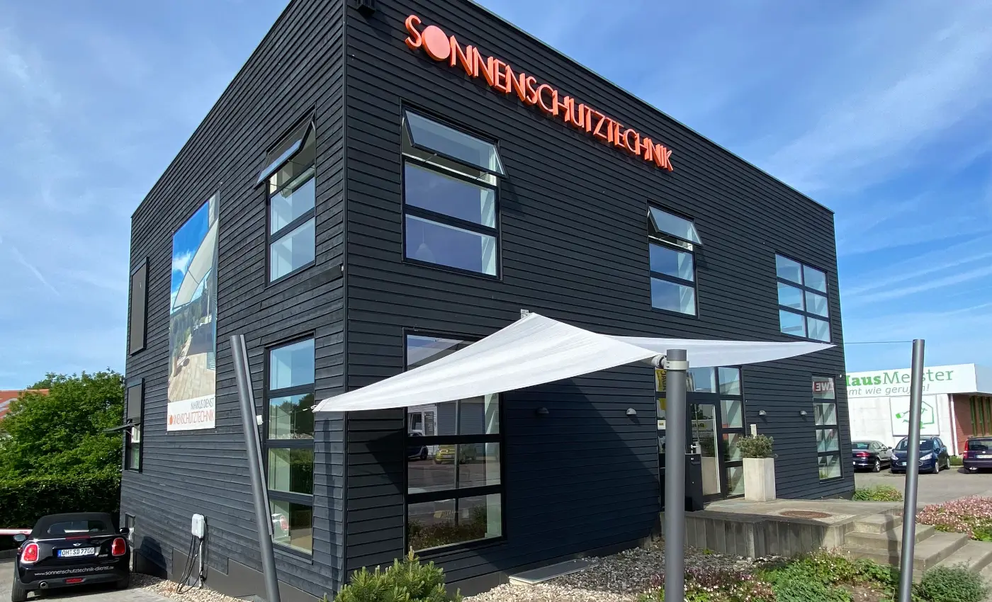 Firmengebäude von Sonnenschutztechnik Dienst mit dunkler Fassade und orangem Schriftzug.