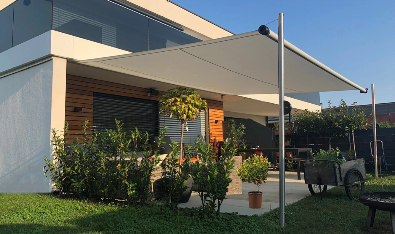 Eine rundum bepflanzte Terrasse wird von einer Shadesign SHADE INOX beschattet.