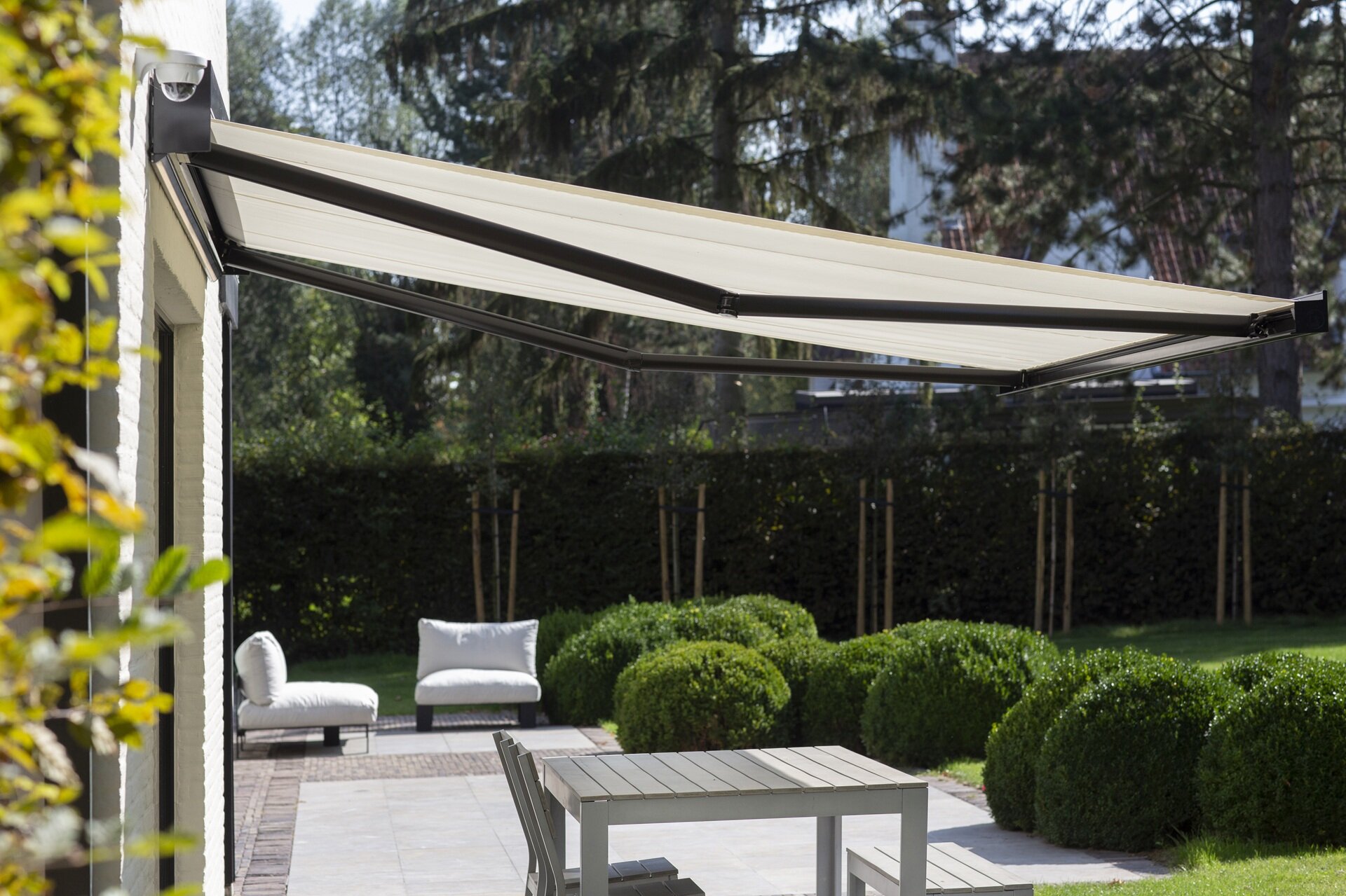Ausgefahrene Markise mit dunkelgrauen Gelenkarmen und hellem Stoff.