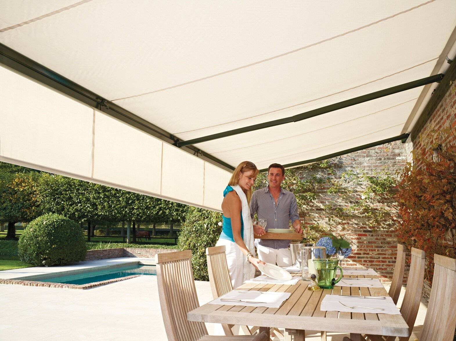 unter einer Markise steht ein junges Paar an einem Esstisch