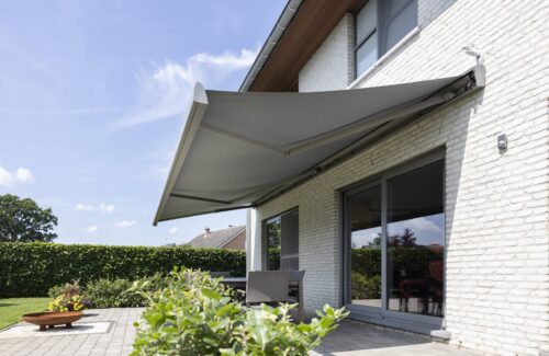ausgefahrene Markise mit hellgrauem SToff und grauem Gestell beschattet eine darunter liegende Terrasse und 2 große Terrassenfenster