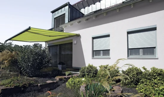 Moderne Markise an einem Einfamilienhaus mit gepflegtem Garten
